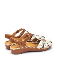 Sandales en cuir marron avec découpes florales blanches, bride réglable, semelle matelassée et détail de couture le long du bord.