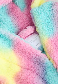 Couverture en polaire aux couleurs pastel avec une texture duveteuse, présentant un dégradé de nuances de rose, bleu et jaune. L'étiquette indique "nightwear by NEXT."