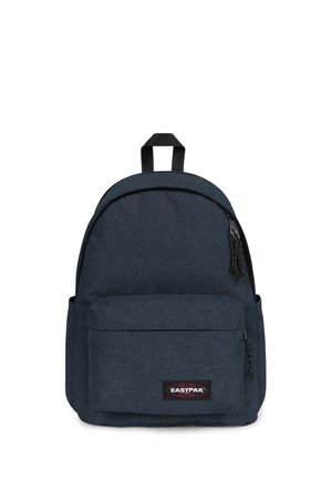 Mochila de tela azul con parte superior redondeada, bolsillo frontal y parche con logo. Presenta cremalleras negras y material texturizado. Correillas ajustables.