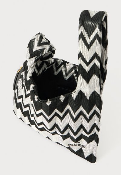 Fekete-fehér cikk-cakk mintás kézitáska, szőtt anyagból készült, egyedi formájú füllel és cipzáras rekesszel.