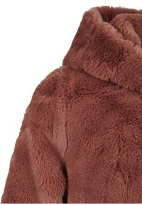 Manteau en fausse fourrure marron avec une finition douce et texturée. Il possède une capuche et une coupe ample, présentant une surface légèrement irrégulière et duveteuse.