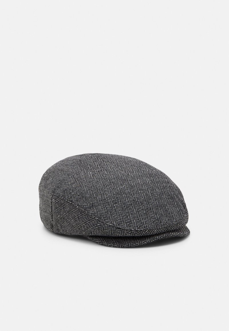 Casquette plate grise avec un motif en chevrons, dessus arrondi et petite visière, présentée sur un fond clair uni.
