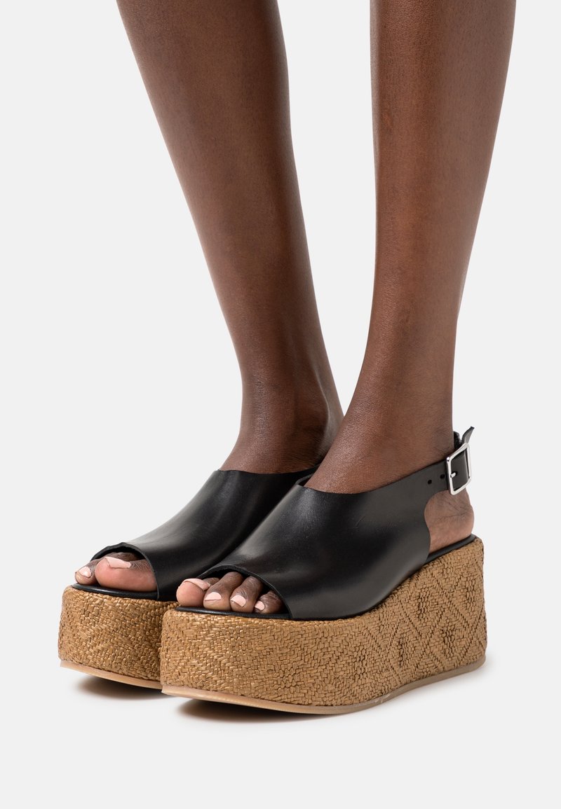 Černé kožené sandály na platformě s otevřenou špičkou a náramkem kolem kotníku, s texturovaným opleteným jutovým klínem a geometrickým vzorem.