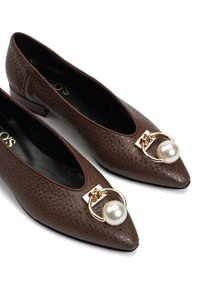 Brązowe, teksturowane skórzane buty z noskiem w szpic na niskim obcasie typu klocek, zdobione złotym pierścieniem i dużą perłą na przodzie.