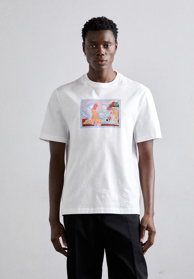White short-sleeve cotton t-shirt featuring a colorful graphic print of two figures and floral accents, with a relaxed fit and crew neckline.