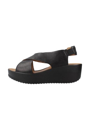 Sandales à talons compensés en cuir noir avec un design à bout ouvert, présentant des découpes et une sangle arrière ajustable. Semelle épaisse et texturée de couleur noire.
