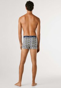 Herrenboxershorts in einer enganliegenden Ausführung. Weißer Stoff mit schwarzem "Pepe Jeans London" Textmuster. Elastischer Bund in Marineblau.