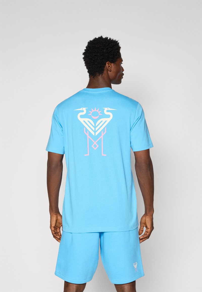 Blue cotton t-shirt with a graphic design featuring two birds and a sun on the back. The fabric appears soft and casual in style.