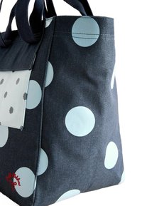 Denim pasējo soma ar lieliem gaiši ziliem punktiņiem, kvadrātveida priekšējo kabatu no gaismas auduma un kontrastējošām tumšām rokturēm. Sarkanā izšūtā detaļa.