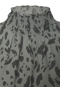 Tessuto verde con un motivo di stampa animale nera, caratterizzato da un collo a smock arricciato e una consistenza morbida. Design strutturato con pieghe fluttuanti.