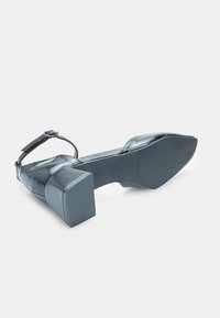 Black heeled sandal with adjustable ankle strap, square block heel, textured synthetic upper, and smooth rubber outsole.