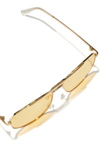 Auksiniai saulės akiniai su geltonais lęšiais, plonu rėmeliu ir stilingais akcentais ant šonų, blizgiu paviršiumi.