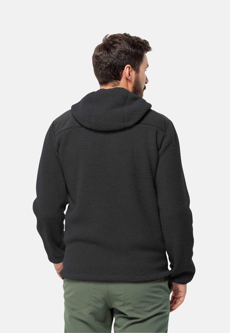 Giacca in pile nera con superficie testurizzata, cappuccio e accenti neri a contrasto sulle spalle. Presenta una tasca con zipper di lato.