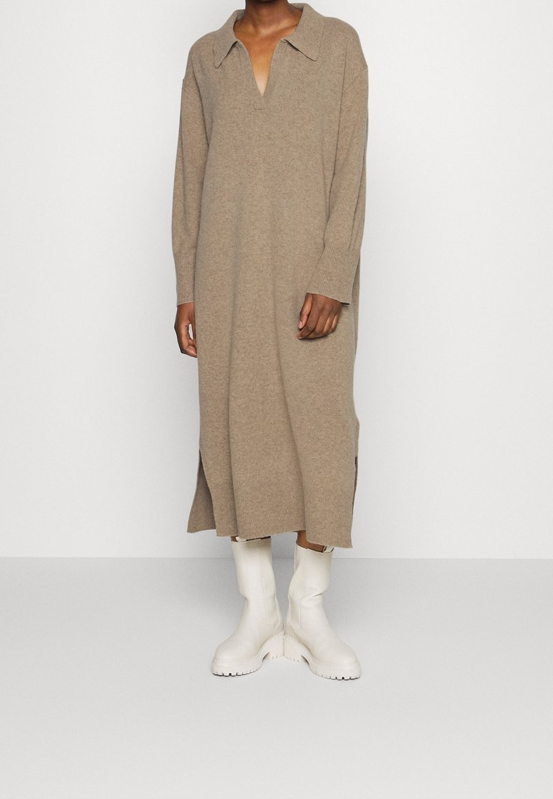 Beige stickad klänning med krage, långa ärmar, sidospår, kombinerad med vita ankelskottar. Mjuk textur och löst passform.