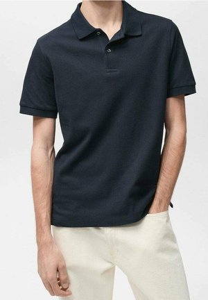 Polo azul marino hecho de algodón suave con cuello clásico, tres botones y mangas cortas. Se lleva con pantalones de color claro.