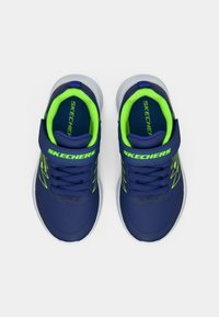 Zilu un neona zaļi Skechers bērnu sporta apavi ar Velcro siksnām, zilām šņorēm un baltām zolēm, skatīti no augšas.