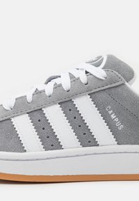 Baskets en suede gris avec des rayures en cuir blanc. Caractéristiques d'une semelle en caoutchouc, d'un bout rond et d'une finition texturée. Comprend des lacets blancs et des détails de marque.