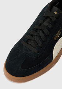 Black suede sneaker with black laces, featuring a white PUMA logo and a gum rubber sole. Smooth texture and classic silhouette.