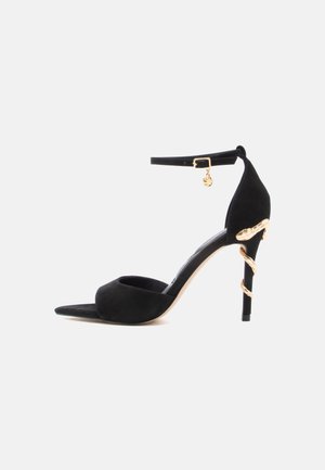 Mustast seemisnahast kõrged kontsakingad, millel on teravaotstik, pahkluu rihm ja kanna kuldsed dekoratiivsed detailid. Sile tekstuur, elegantne disain.