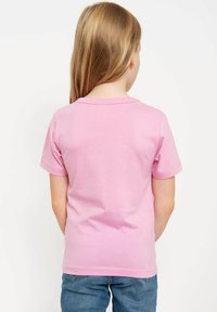 Rosa kurzärmliges Baumwoll-T-Shirt mit rundem Ausschnitt, glatter Textur und kontrastierenden Nähten am Saum, kombiniert mit Jeans.