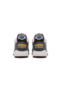 Sneaker in suede grigio con accenti bianchi e neri. Presentano un collare imbottito e un logo giallo sul tallone. Suola in gomma per aderenza.