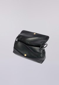 Svart läderhandväska med texturerad finish, öppen topp och placerade handtag. Har detaljer i guldton och en minimalistisk design.