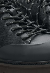 Černé kožené turistické boty s texturovaným svrškem, pevnou gumovou podrážkou a tmavými tkaničkami s jasnými akcenty, navržené pro trvanlivost a pohodlí.