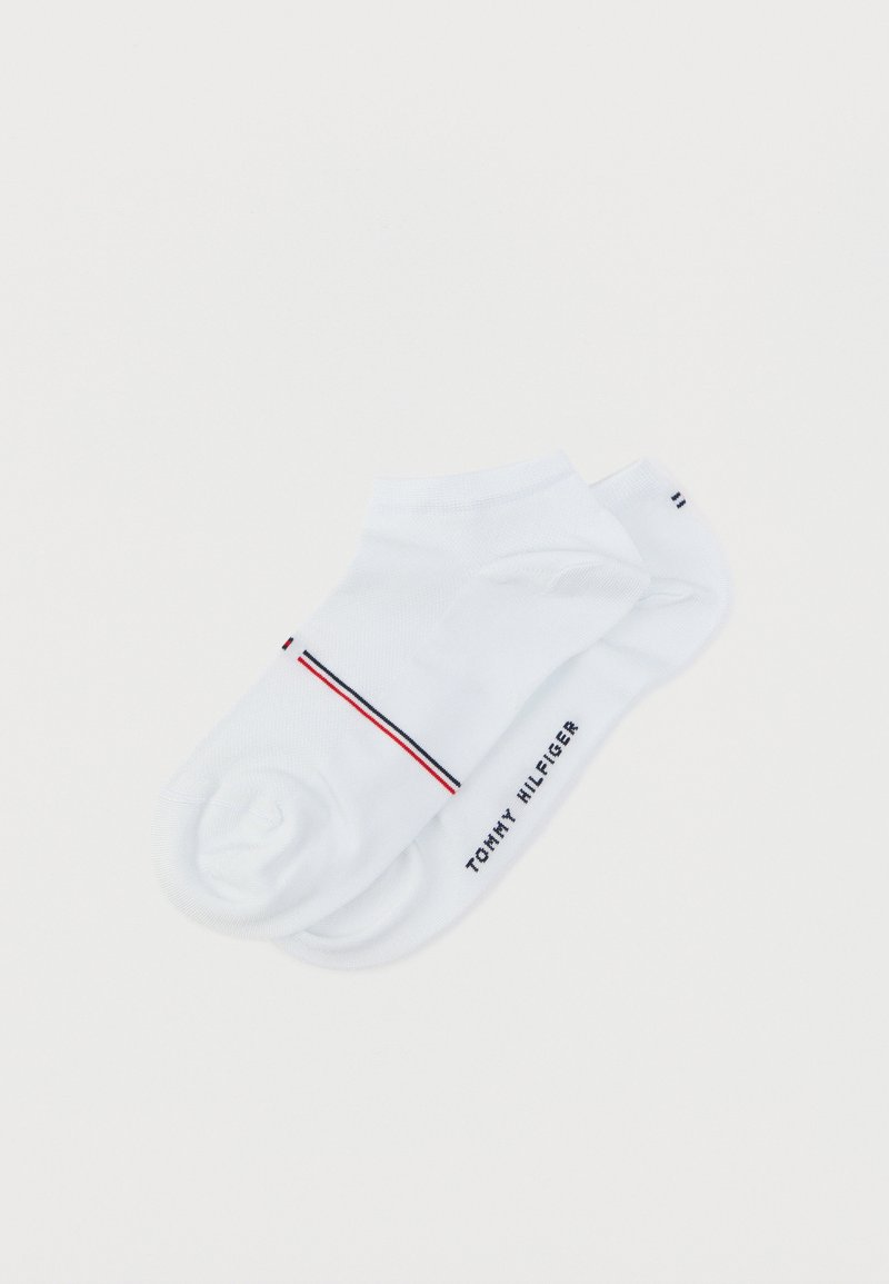 Ζευγάρι λευκά κάλτσες αστραγάλου με το λογότυπο Tommy Hilfiger και κόκκινες και ναυτικές ρίγες, απλωμένες επίπεδα σε λευκό φόντο.