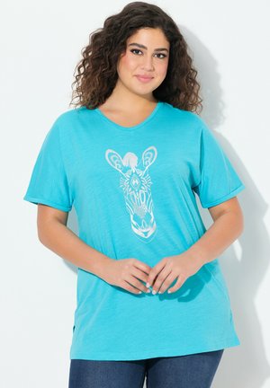 T-shirt turquoise à manches courtes en tissu doux, avec un design graphique de girafe blanche sur le devant. Ourlet droit et col rond.