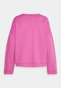 Sudadera rosa con un corte holgado, escote redondo y mangas largas. Textura suave y sin patrones visibles. Presenta costuras overlock.