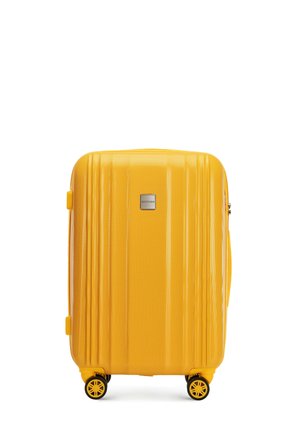 Yellow hardshell suitcase with vertical ridges, a silver brand plate, and four black spinner wheels for easy mobility.