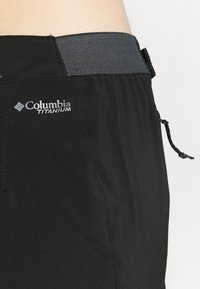 De sorte Columbia Titanium-shorts har et glat stof, elastisk taljebånd med grå accenter og en snor til justering.