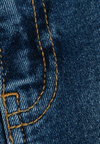 Jeans tyg i mörkblått med synlig textur. Kontraststygn i gult skapar dekorativa linjer och former på ytan.