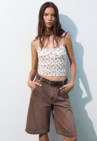 Blomsterprintet smocked crop top, let stof; brune denimshorts med sidelommer og et øje-bælte, der har en glat tekstur og afslappet pasform.