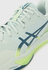 Lys blå atletisk sko med en pustende mesh-overdel, marineblå detaljer, strukturert design, og en gult-grønn såle med FF Blast+-teknologi.
