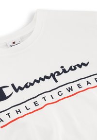 Camiseta de algodón blanca con un destacado logo negro de "Champion" y "ATHLETICWEAR" en negrita, acentuado con una línea roja.