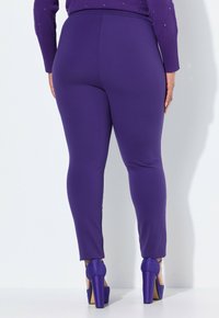 Lila leggings med en slät textur och en tajt design, tillsammans med matchande högklackade skor.