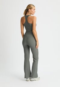 Completo activewear verde oliva composto da un top aderente con design a razzo e pantaloni svasati con finitura testurizzata.