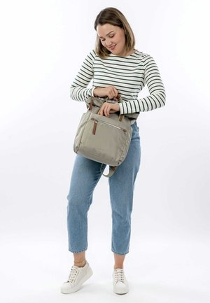 Lichtgrijze tote bag met een stoffen buitenkant, twee handvatten bovenaan en een voorzak met rits. Voorzien van bruine leren accenten en een verstelbare schouderband.