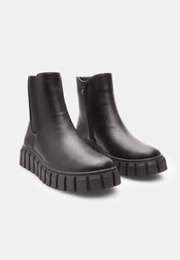 Botine negre din piele cu talpă din cauciuc chunky, închidere cu fermoar pe lateral și finisaj texturat. Design elegant cu vârf rotunjit și părți elastice.