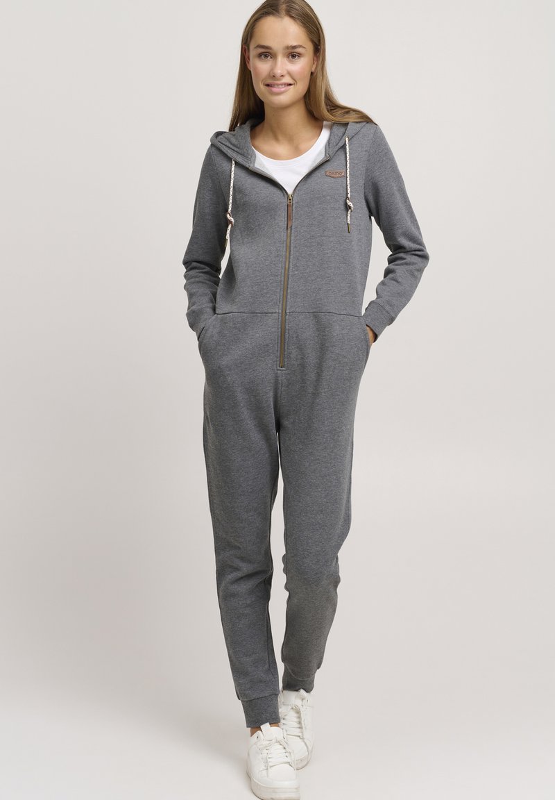 Salopette in cotone grigio misto con zip anteriore, cappuccio, tasche laterali e dettagli con cordino. Polsini a coste e vestibilità morbida.