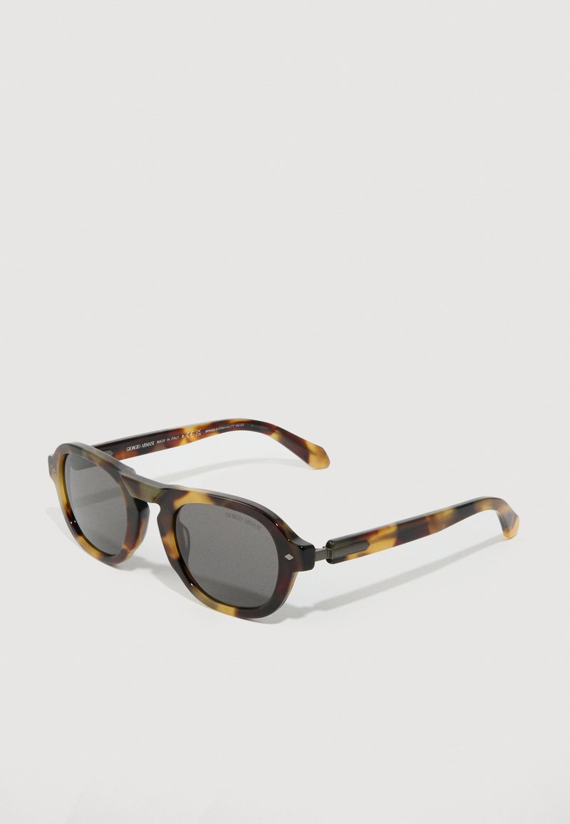 Gafas de sol de patrón carey de Giorgio Armani con lentes oscuros y montura rectangular redondeada sobre un fondo claro y liso.