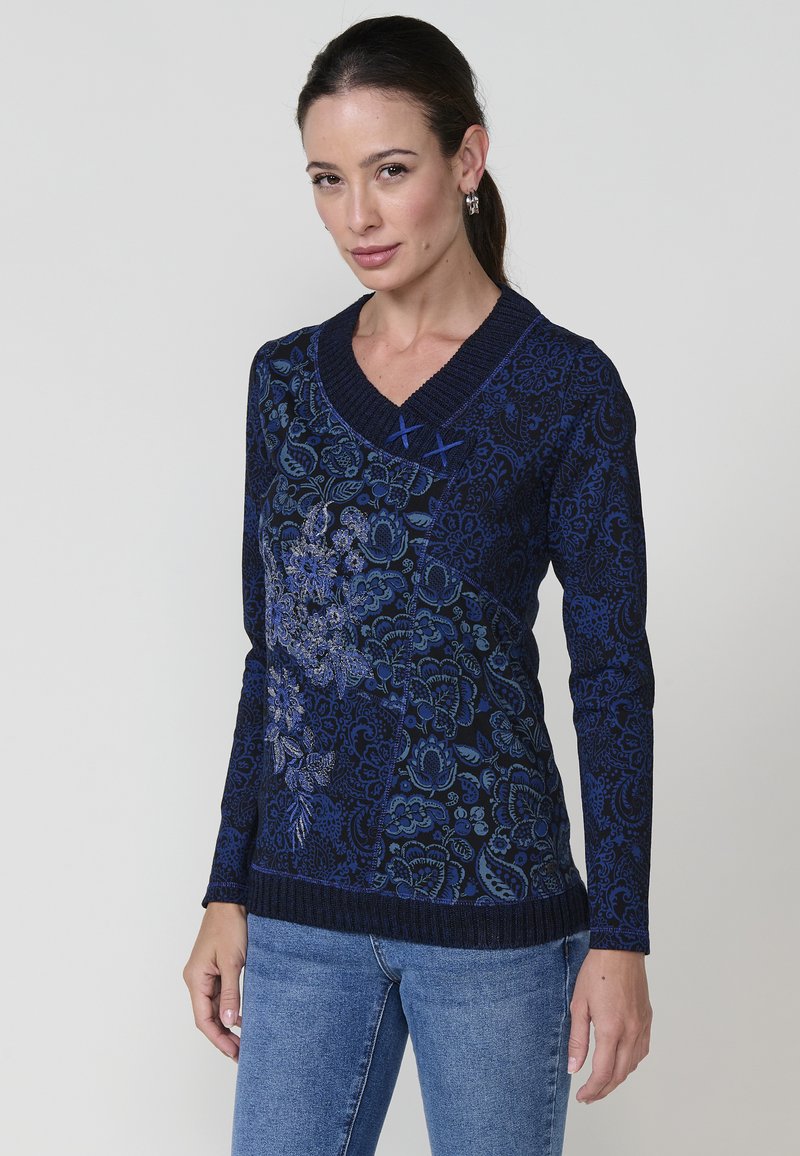 Marineblauer Langarmpullover mit floralem Muster, V-Ausschnitt, geripptem Saum und blauen Nähakzenten am Kragen, aus einem strukturierten Strickmaterial gefertigt.