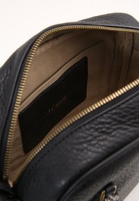 Black leather bag with a textured finish, gold zipper, and beige interior lining. Includes a card pocket and subtle branding inside.