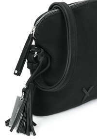 Sorte læder crossbody taske med perforeret tekstur, sølvfarvet lynlås, justerbar rem og frynse detalje med et metalskilt.