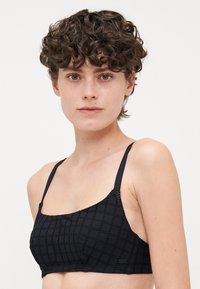 Svart bralette med ett geometriskt mönster, med tunna band och en slät textur. Designad med en fyrkantig necklinje och en minimalistisk stil.