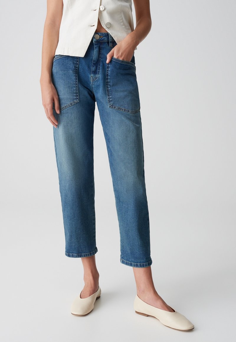 Ljust blå denimjeans med avslappnad passform, inklusive framfickor, medelhögt midja och uppvikta cuffs. Bärs tillsammans med en krämfärgad topp.