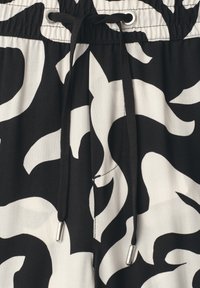 Tissu à motif abstrait noir et blanc avec un cordon noir passé à travers des œillets métalliques à la taille.