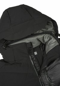 Chaqueta acolchada negra con capucha, que presenta un exterior liso y un forro interior con patrón. Incluye dos bolsillos con cremallera y cordones ajustables.