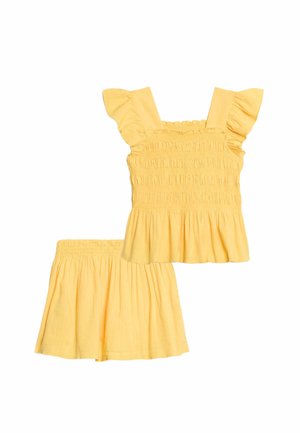 Geel tweedelig outfit met een mouwloos, geplooid top met geruite bandjes en een bijpassende elastische taille rok.